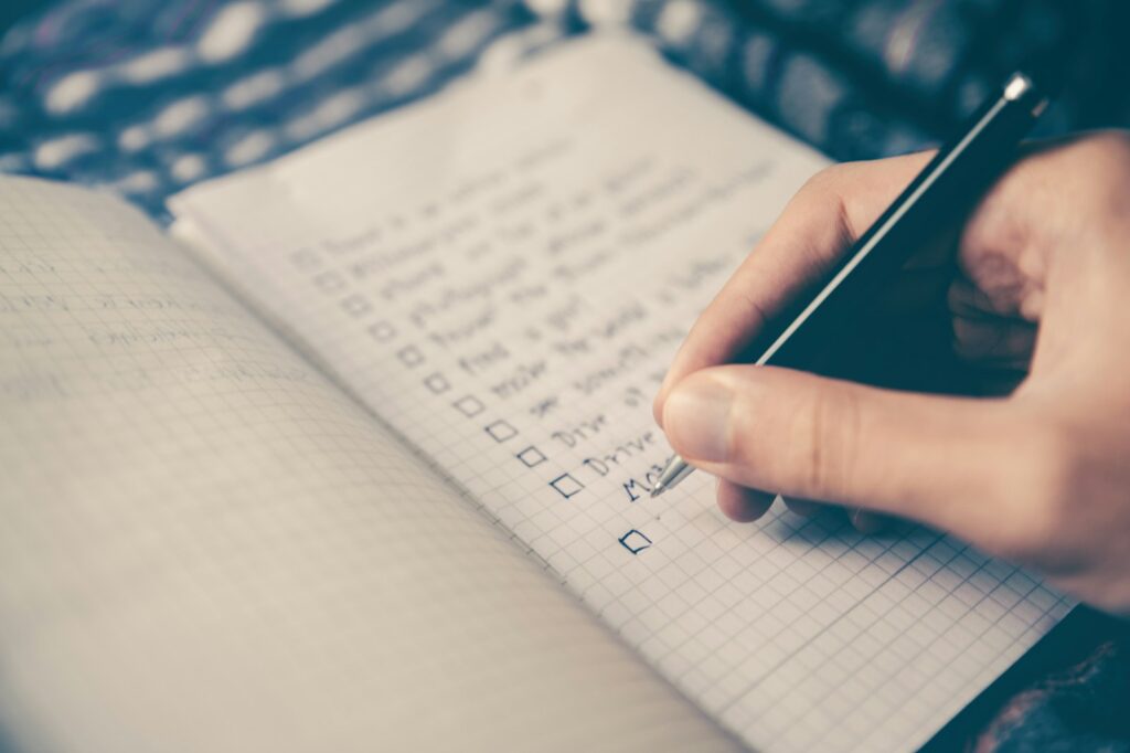 Persona escribiendo una lista a mano en un cuaderno
